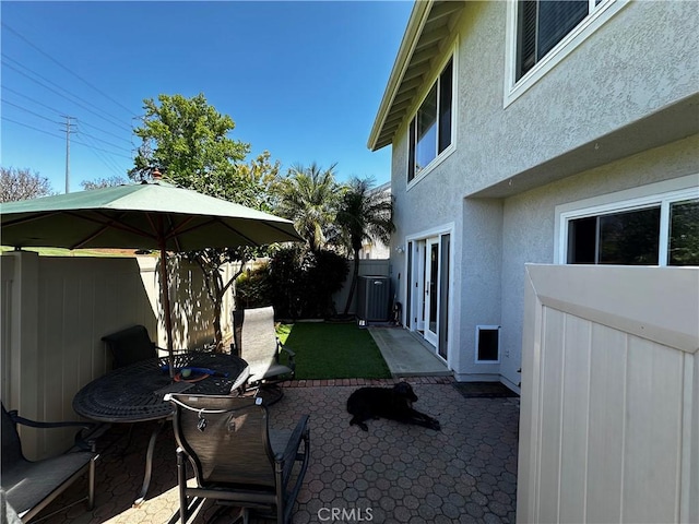 view of yard featuring a patio, fence, and central AC unit
