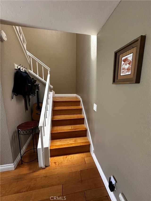 staircase featuring baseboards and hardwood / wood-style floors
