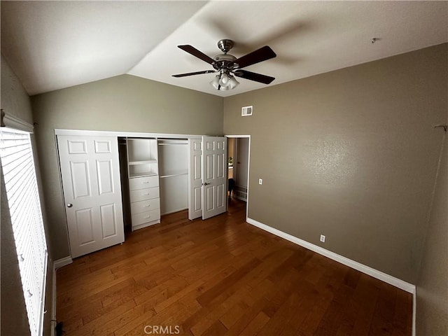 unfurnished bedroom with visible vents, a closet, baseboards, dark wood-type flooring, and vaulted ceiling