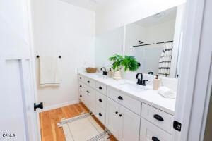 full bathroom featuring double vanity, wood finished floors, baseboards, a shower with curtain, and a sink
