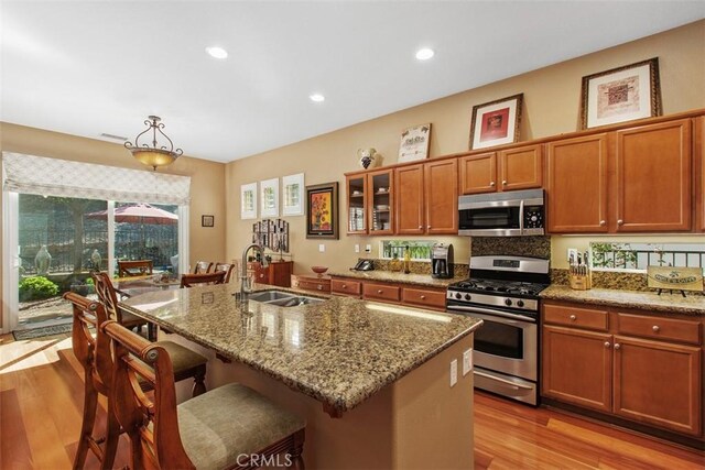 9169 Wooded Hill Dr, Corona, CA 92883 - kitchen with brown cabinetry, a kitchen bar, light wood-type flooring, a sink, and stainless steel appliances