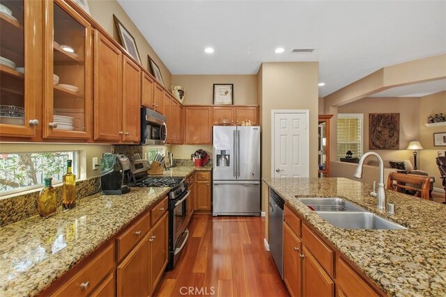 9169 Wooded Hill Dr, Corona, CA 92883 - kitchen with appliances with stainless steel finishes, a sink, brown cabinetry, wood finished floors, and visible vents