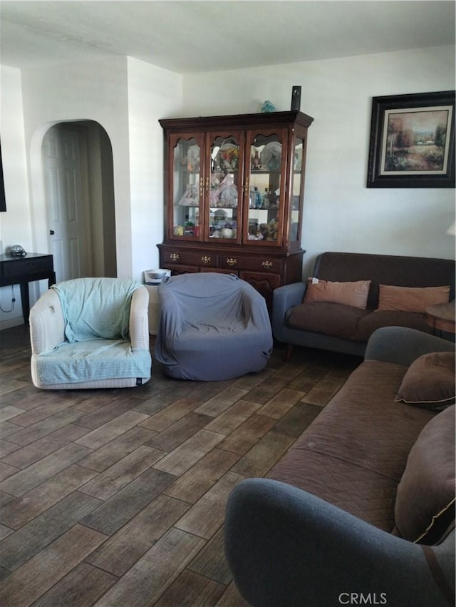 living area featuring arched walkways and dark wood-style flooring