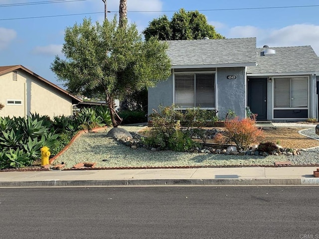 view of front of house with stucco siding and a shingled roof