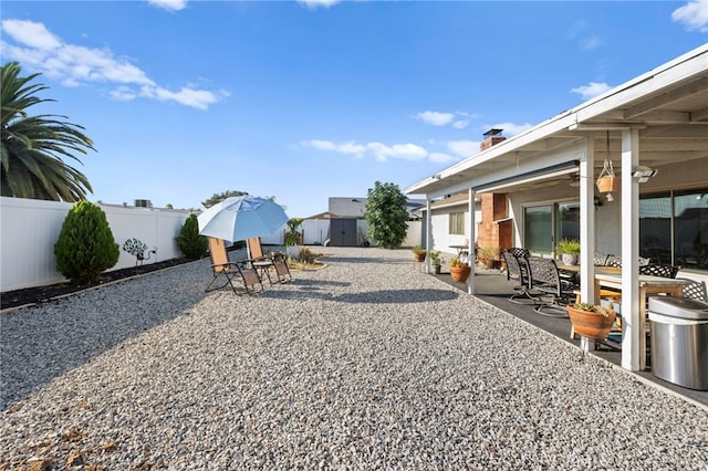 view of yard featuring a fenced backyard, a storage unit, outdoor dining area, and a patio area