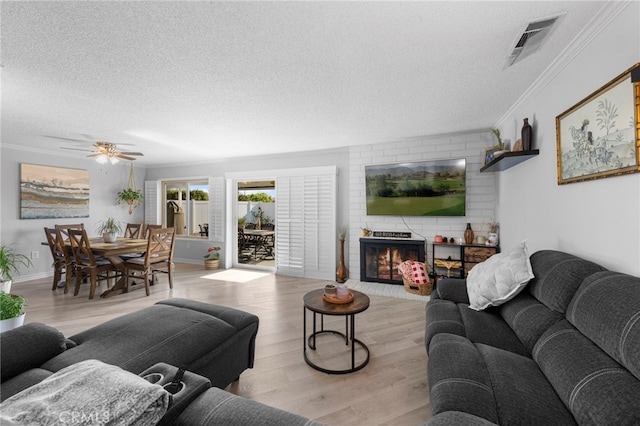 living area with ornamental molding, a fireplace, a textured ceiling, and visible vents