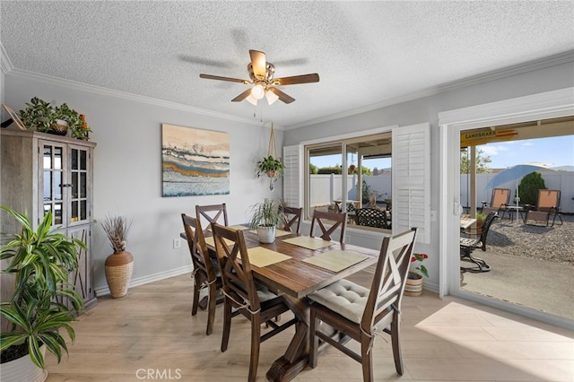 dining space with ceiling fan, a textured ceiling, baseboards, light wood finished floors, and ornamental molding