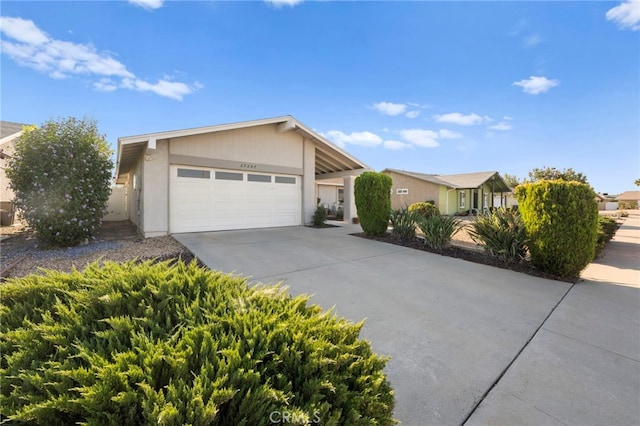 view of front of property featuring concrete driveway, an attached garage, and stucco siding