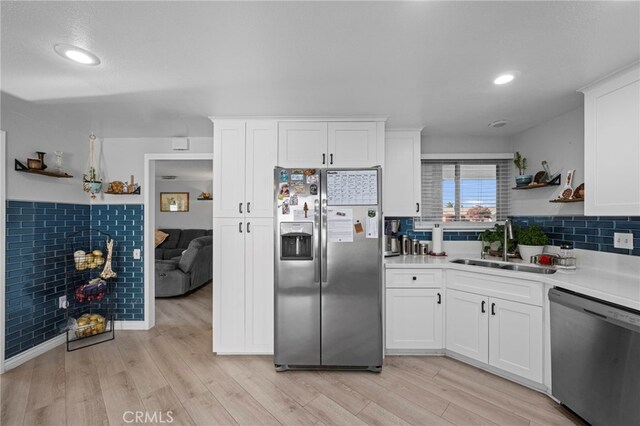 kitchen with light wood-type flooring, a sink, white cabinets, and stainless steel appliances