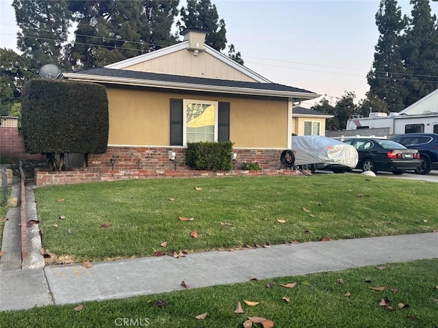 view of property exterior with stucco siding, stone siding, and a lawn