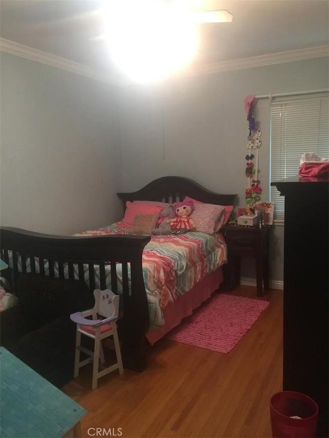 bedroom with crown molding and wood finished floors