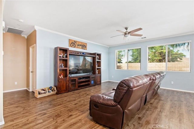 living area featuring a ceiling fan, visible vents, wood finished floors, baseboards, and ornamental molding