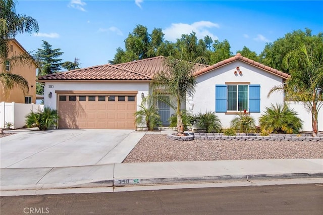 view of front facade with fence, an attached garage, concrete driveway, and stucco siding