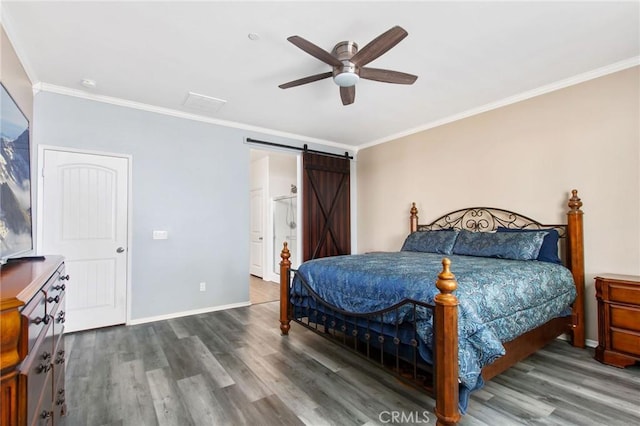 bedroom featuring crown molding, baseboards, a barn door, and wood finished floors
