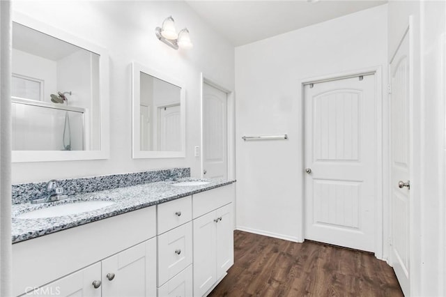 full bath featuring double vanity, baseboards, a sink, and wood finished floors