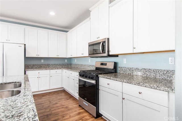 kitchen featuring light stone countertops, wood finished floors, stainless steel appliances, recessed lighting, and white cabinetry