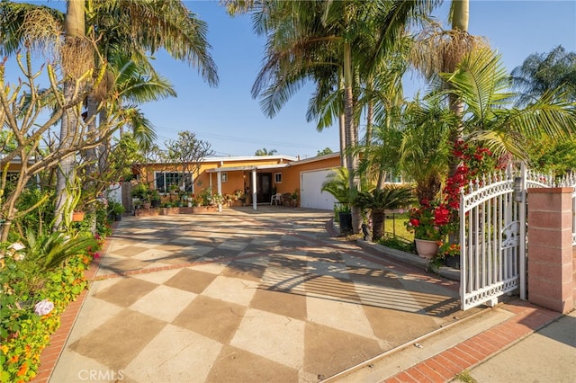 view of front facade with concrete driveway, stucco siding, a gate, and a garage