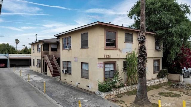 exterior space with stucco siding, stairway, and cooling unit