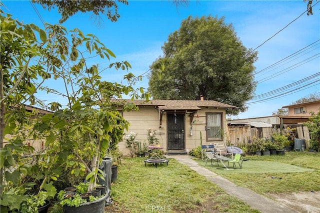 rear view of house with a lawn, fence, and central AC unit