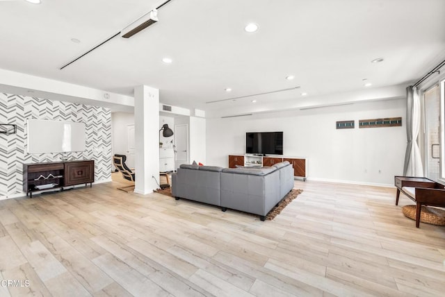 living area with an accent wall, baseboards, recessed lighting, and light wood finished floors
