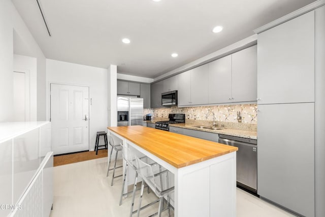kitchen with a sink, appliances with stainless steel finishes, a kitchen breakfast bar, and wood counters