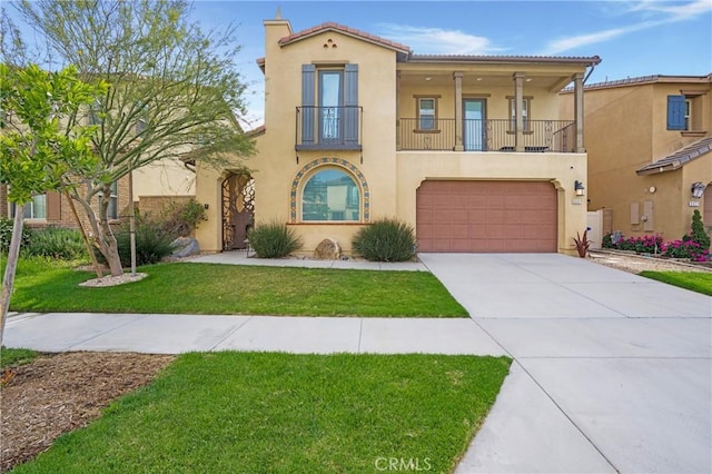mediterranean / spanish-style house featuring driveway, a front yard, a garage, a balcony, and stucco siding