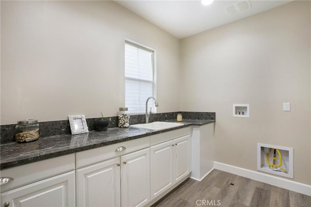 clothes washing area with light wood-style floors, baseboards, hookup for a washing machine, a sink, and cabinet space