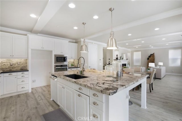 kitchen with decorative backsplash, beam ceiling, white cabinets, a sink, and appliances with stainless steel finishes