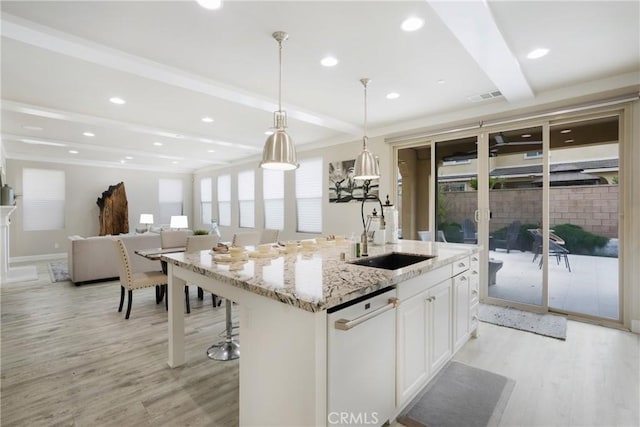 kitchen with visible vents, light wood-type flooring, beam ceiling, dishwasher, and a sink