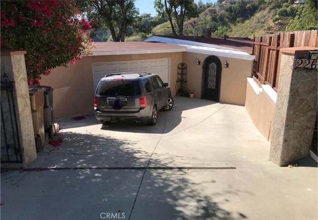 exterior space with a garage, stucco siding, driveway, and fence
