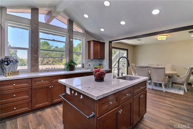 kitchen with decorative backsplash, dark wood-style flooring, a sink, light stone counters, and vaulted ceiling with beams