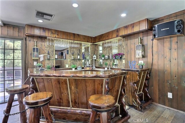 bar featuring wooden walls, indoor wet bar, and visible vents