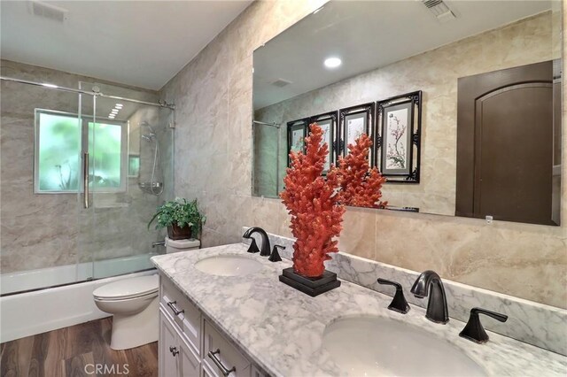 full bathroom with a sink, tile walls, wood finished floors, and visible vents