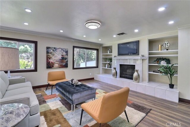 living area featuring crown molding, recessed lighting, wood finished floors, and visible vents