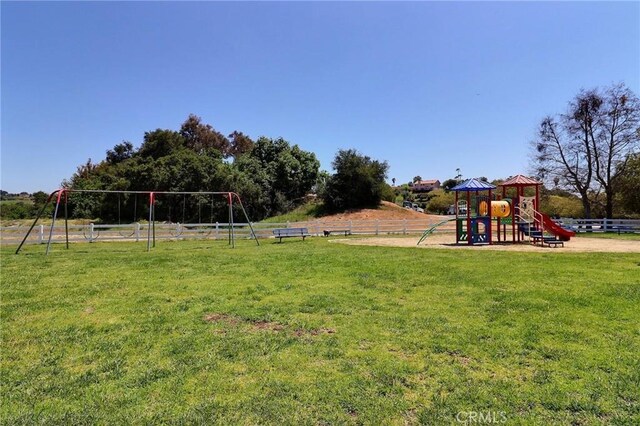community jungle gym featuring a lawn and fence