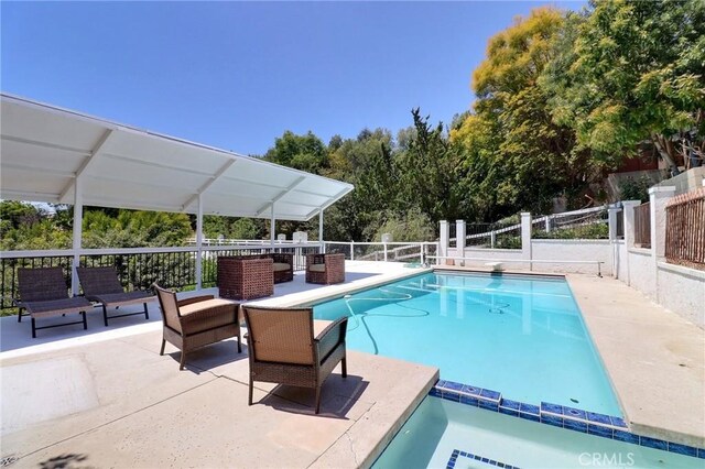 view of pool with fence, a fenced in pool, an outdoor living space, and a patio area