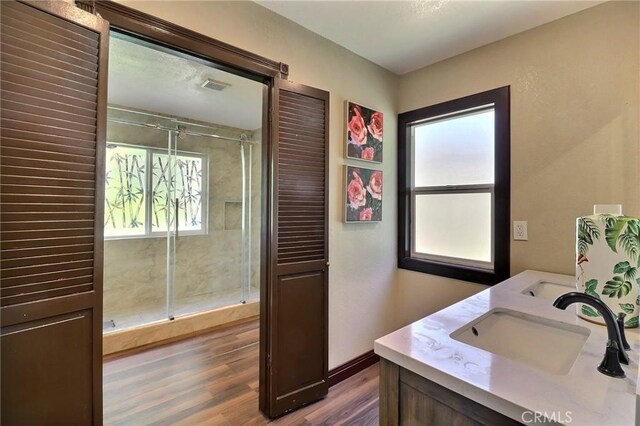 bathroom with a sink, baseboards, a shower stall, wood finished floors, and visible vents