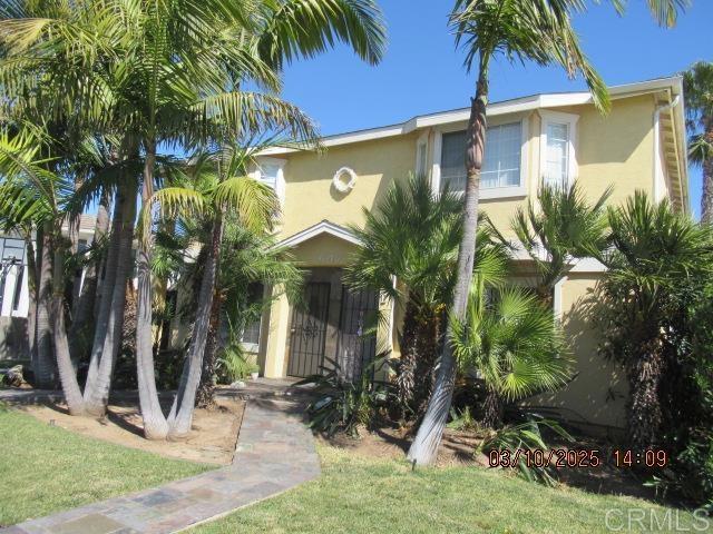 view of front of home featuring stucco siding and a front yard