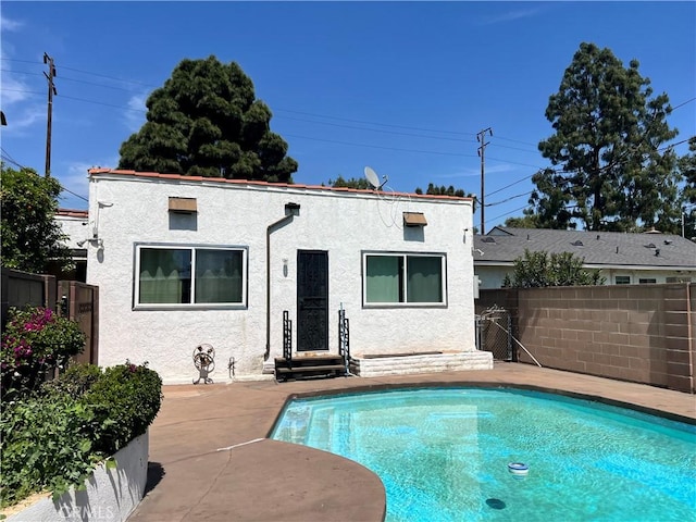 back of house with a fenced in pool, stucco siding, and fence