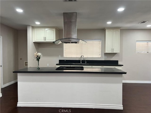 kitchen with a sink, dark countertops, range hood, and baseboards