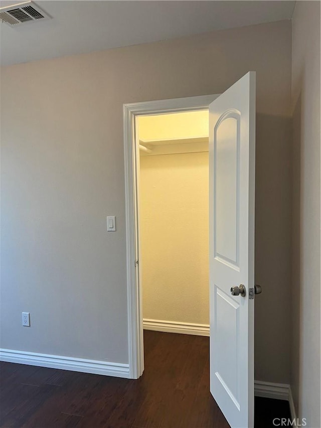 unfurnished bedroom featuring baseboards, dark wood finished floors, and visible vents