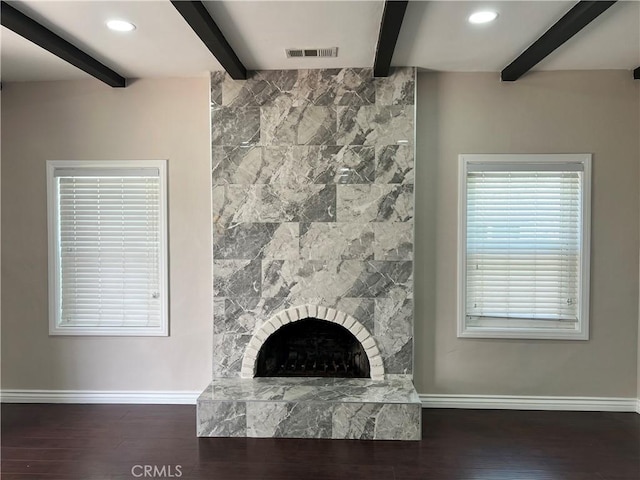 unfurnished living room featuring baseboards, beam ceiling, visible vents, and wood finished floors