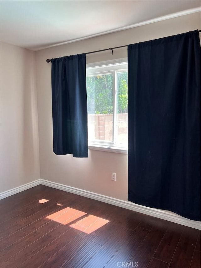 empty room featuring dark wood-style flooring and baseboards