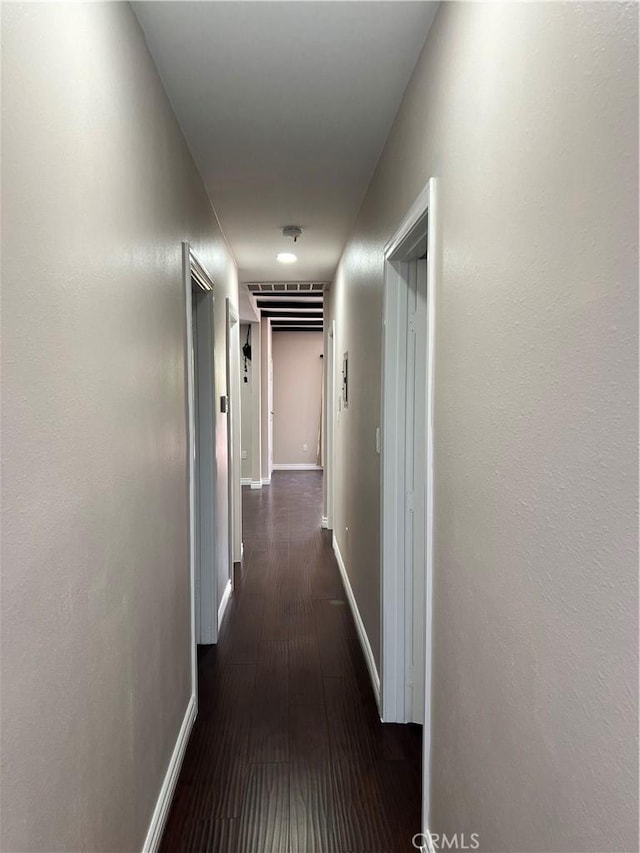 hallway featuring baseboards and dark wood-style flooring