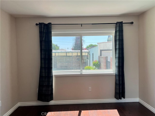 spare room featuring baseboards and wood finished floors