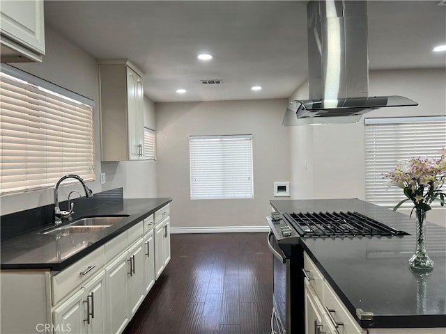 kitchen featuring a sink, wall chimney exhaust hood, stainless steel gas range oven, and dark countertops