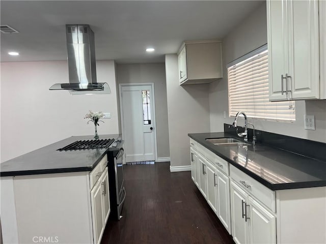kitchen featuring dark countertops, a sink, ventilation hood, stainless steel range with gas stovetop, and visible vents