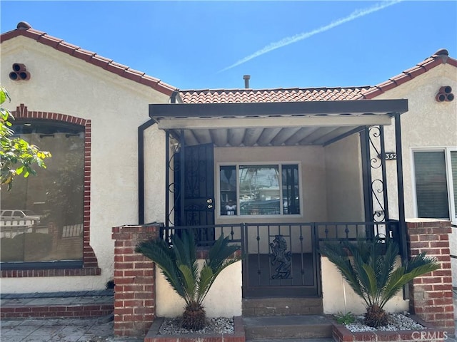 view of exterior entry with stucco siding and a tile roof