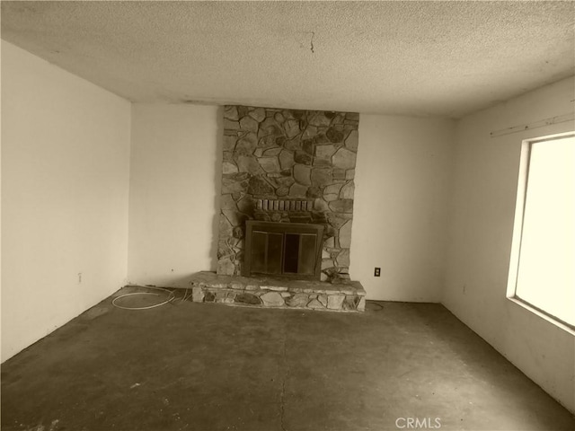 unfurnished living room with a stone fireplace and a textured ceiling