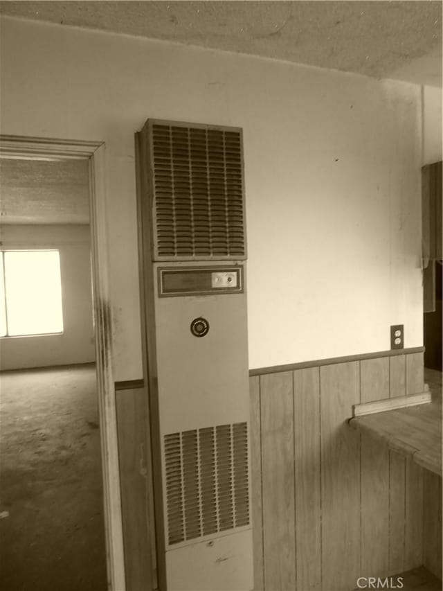 details with a textured ceiling, a heating unit, and a wainscoted wall